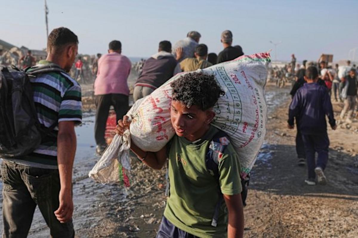 Một cậu bé Palestine mang theo bao tải thực phẩm và viện trợ nhân đạo được dỡ xuống từ đoàn xe của Chương trình Lương thực Thế giới.